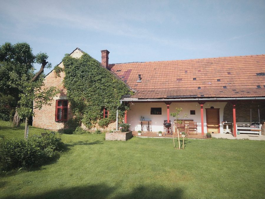 Stavení s verandou a široký trávník se stromy