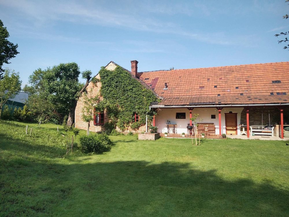 Valašské stavení s břečťanem na cihlovém štítu, červenými sloupky verandy a velkou zahradou