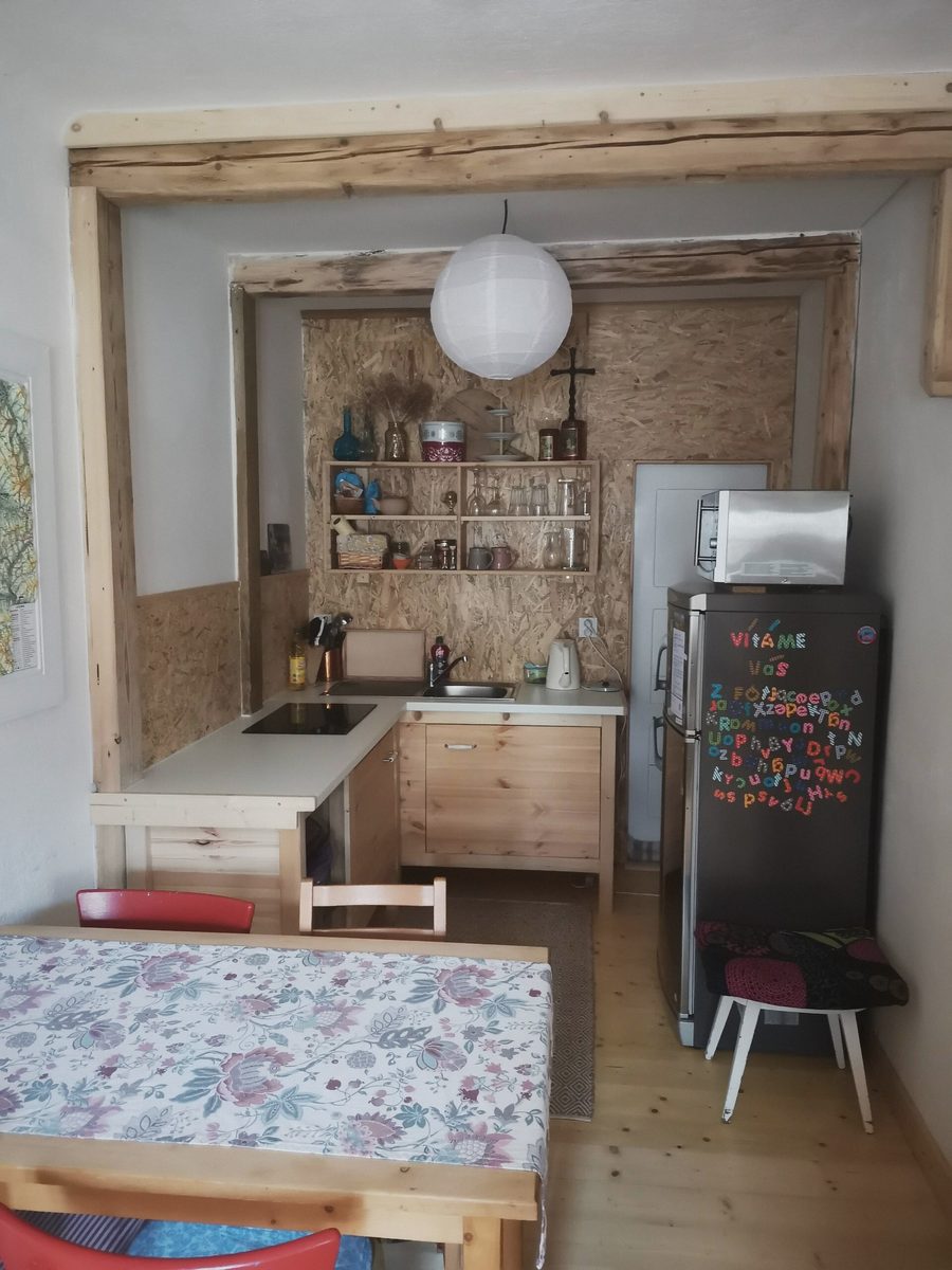 Kuchyňka s policemi, lednicí a stolem